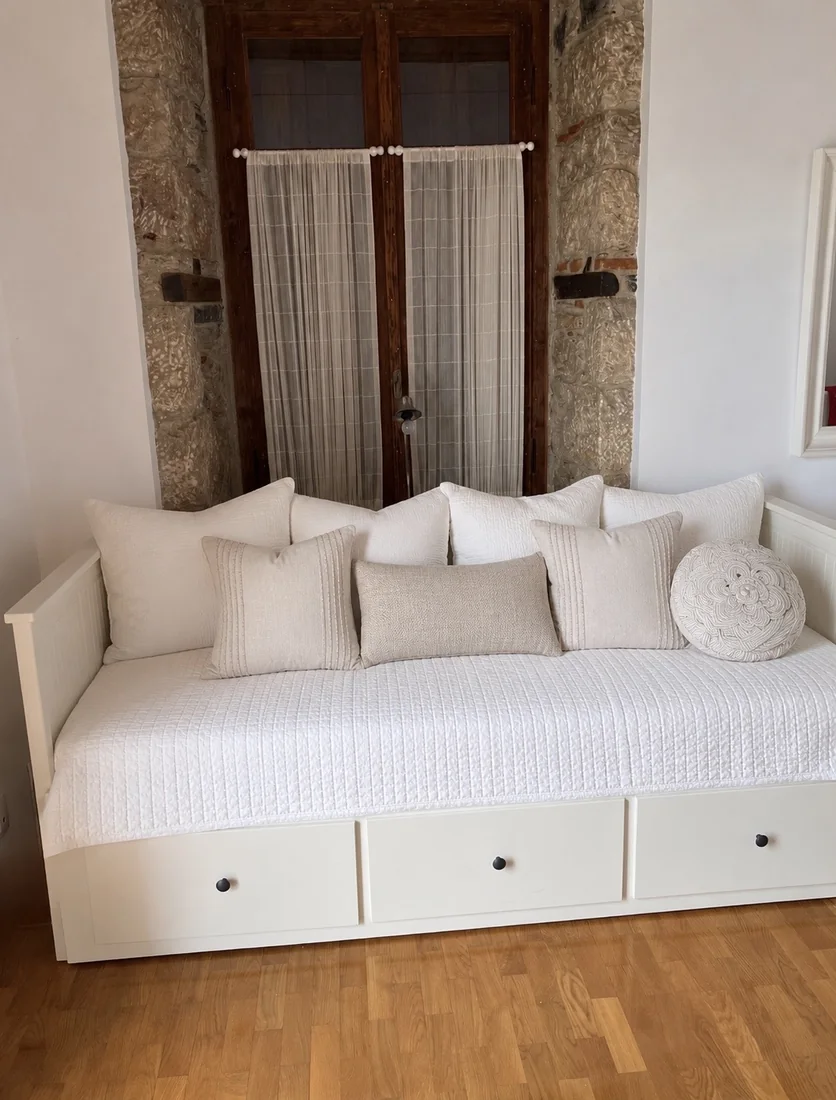White daybed with neutral cushions in a bright guest room at Villa Arcadia