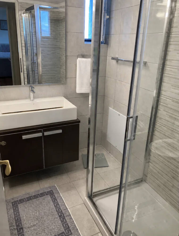 Stone-tiled bathroom with glass shower and dark wood vanity at Villa Arcadia