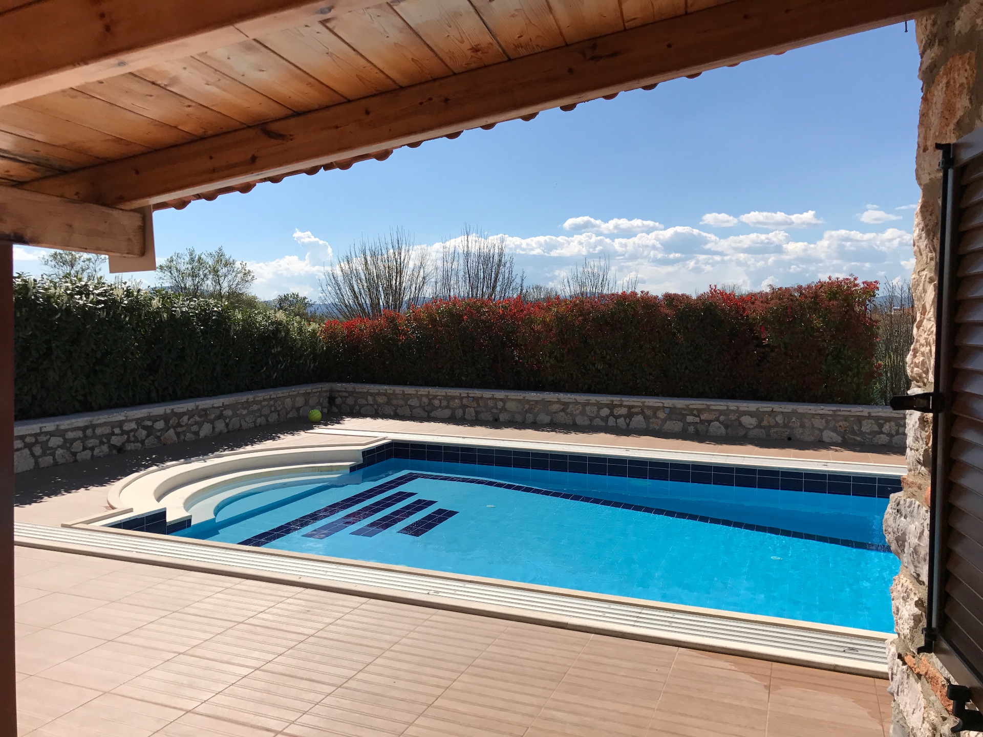 Villa Arcadia pool seen from the covered stone terrace with mountain views