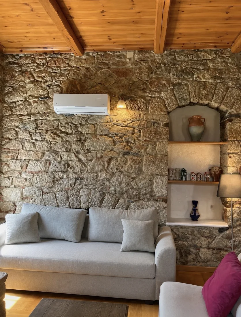 Living room sofa against a warm stone wall inside Villa Arcadia